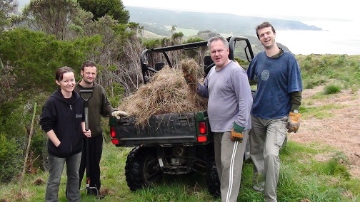 course standing in from of farm buggy with load of grass on the back